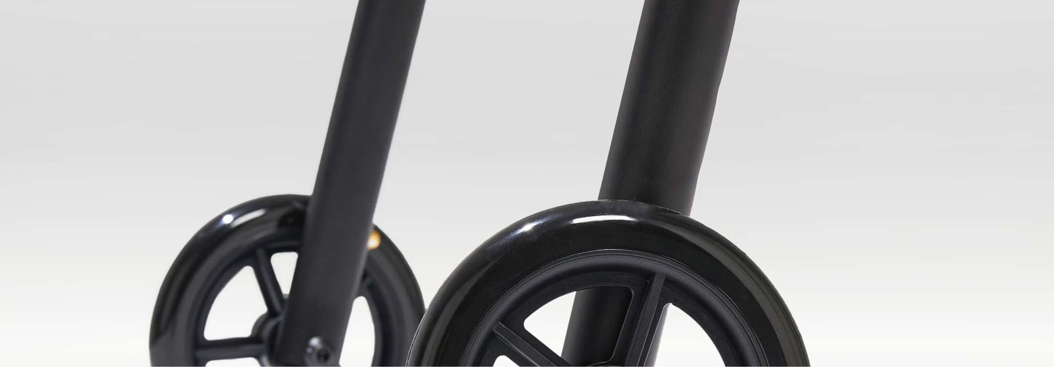 Close-up of black scooter wheels on a light gray background