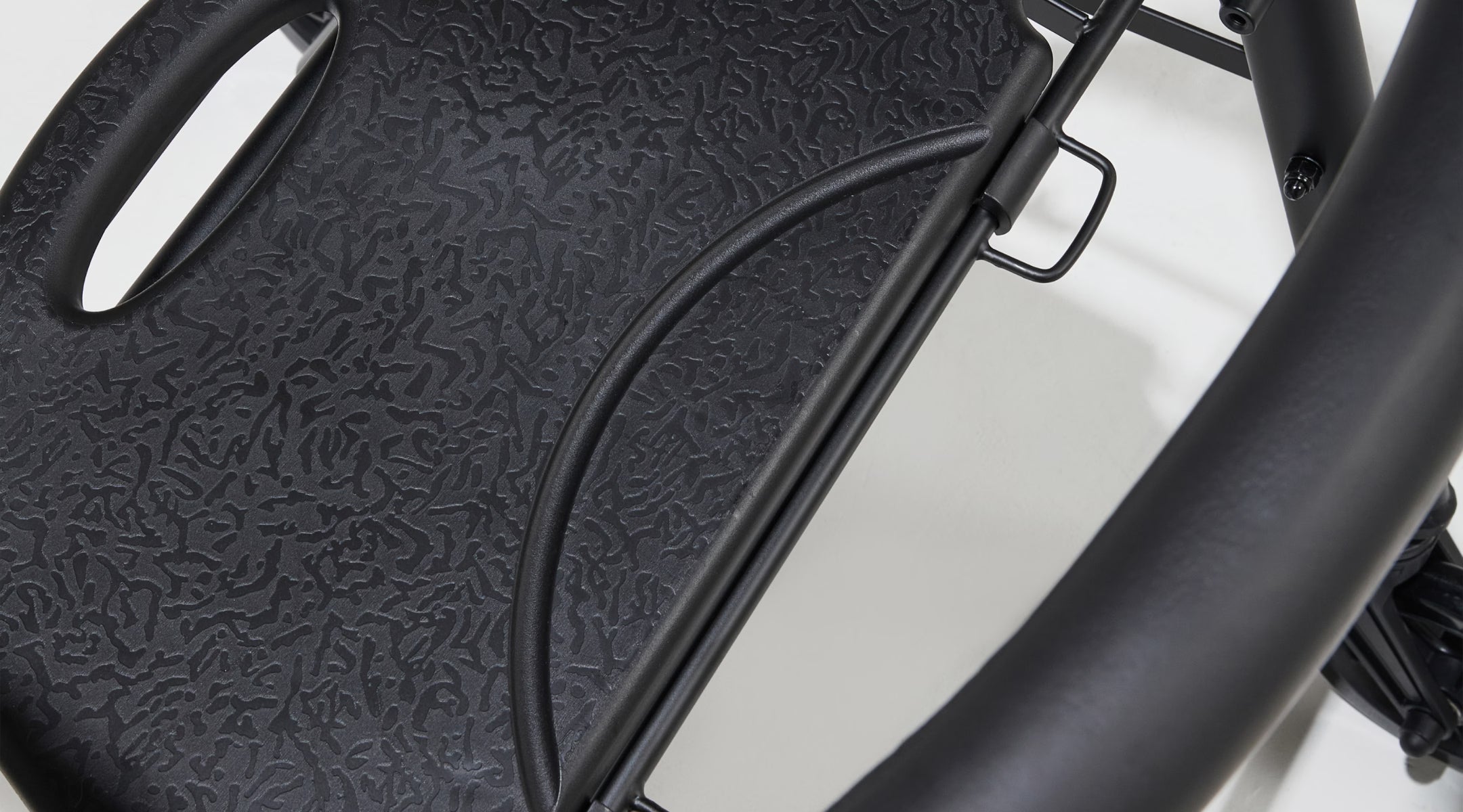 Close-up of a black textured surface with a handle and cable on a white background