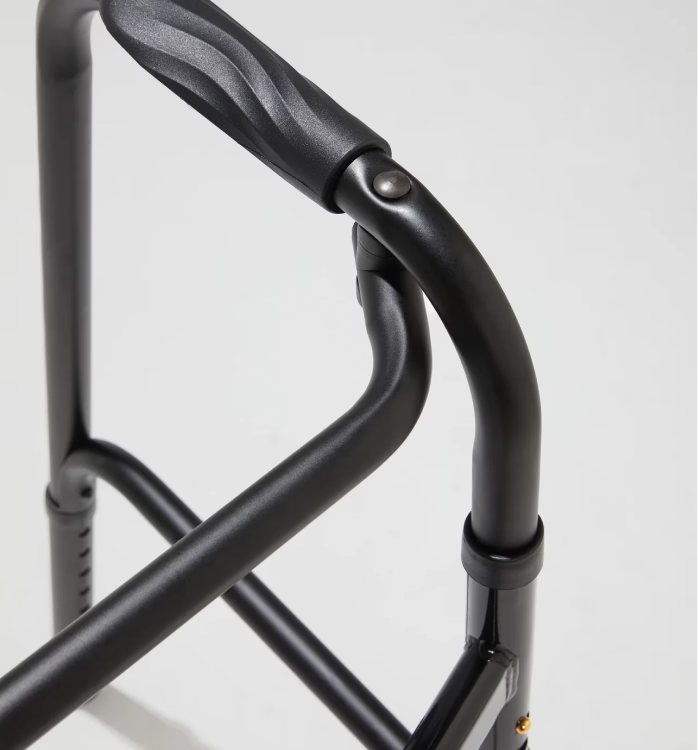 Close-up of a black metal walker handle on a light gray background