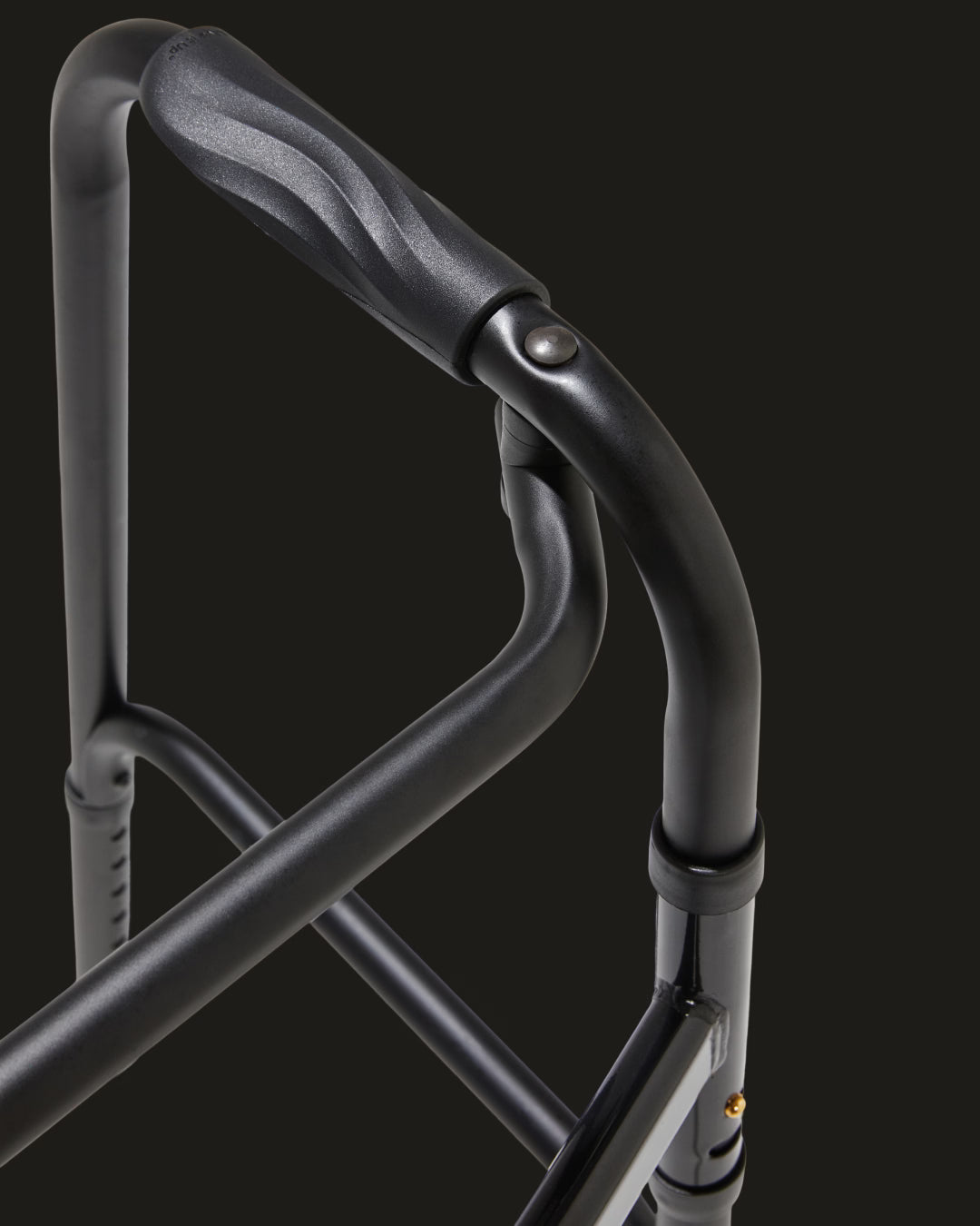 Close-up of a black metal walker handle on a dark background